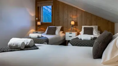 a bedroom with two beds and two lamps and a window at La Snaille des Planards in Chamonix-Mont-Blanc
