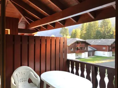 a white chair on a balcony with a view of a house at Studio avec balcon et animaux admis - FR-1-629-92 in Samoëns