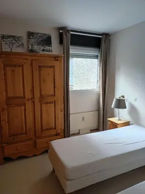 a bedroom with a white bed and a window at Appartement proche village et remontées mécaniques in Saint-Gervais-les-Bains