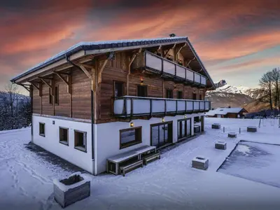 a house in the snow with a sunset at Chalet Woodman - OVO Network in Saint-Gervais-les-Bains