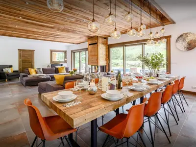 a large wooden table with orange chairs in a living room at Chalet Woodman - OVO Network in Saint-Gervais-les-Bains
