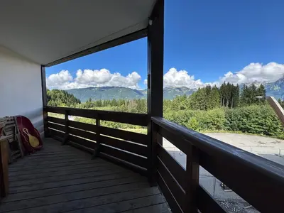 a table and chairs on a deck with a view of mountains at Confortable appartement 3 chambres avec WiFi pour 8 personnes - FR-1-642-7 in Morillon