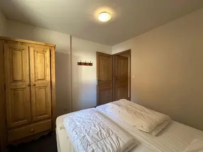 a bedroom with a white bed with a wooden door at Appartement spacieux 4 chambres, pieds pistes, parking inclus - FR-1-642-4 in Morillon