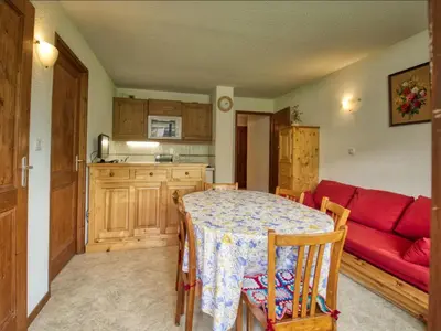 a living room with a table and a red couch at Appartement confortable 6 pers proche jardin enfants - FR-1-642-24 in Morillon