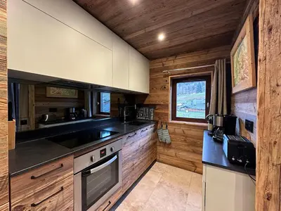 a kitchen with wooden cabinets and a stove top oven at Appartement duplex rénové 6p, expo sud - FR-1-642-56 in Morillon