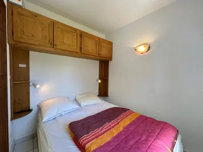 a bedroom with a bed with a striped blanket on it at Appartement cosy 6 pers avec balcon en montagne - FR-1-642-53 in Morillon