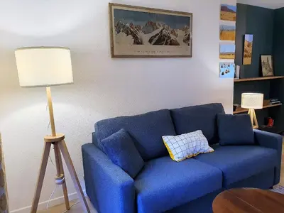 a blue couch in a living room with a lamp at Chamonix Appartement Vue Mont Blanc avec jardin in Chamonix-Mont-Blanc