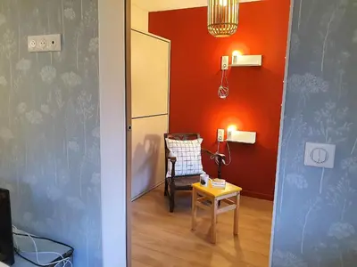 a room with an orange wall and a chair and a table at Chamonix Appartement Vue Mont Blanc avec jardin in Chamonix-Mont-Blanc