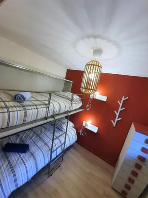 two bunk beds in a room with a red wall at Chamonix Appartement Vue Mont Blanc avec jardin in Chamonix-Mont-Blanc