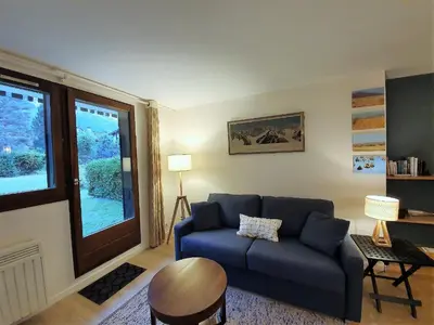 a living room with a blue couch and a window at Chamonix Appartement Vue Mont Blanc avec jardin in Chamonix-Mont-Blanc