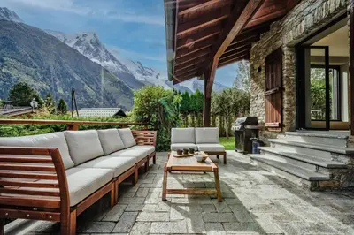 a patio with a couch and a table and mountains at Chalet Alouette in Chamonix-Mont-Blanc