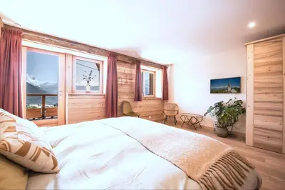 a bedroom with a large bed and a large window at La Ferme des Fingères in Cordon