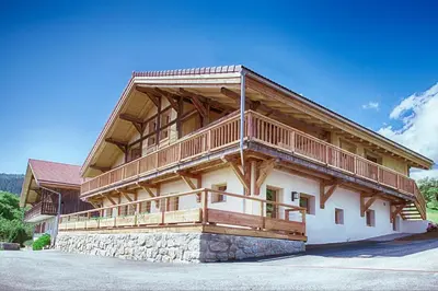 a large wooden house with a large balcony at La Ferme des Fingères in Cordon