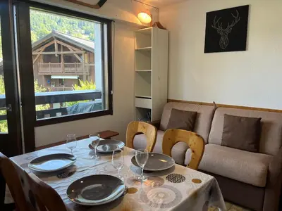 a dining room table with chairs and a couch at Studio chaleureux avec balcon au centre de Samoëns - FR-1-624-83 in Samoëns