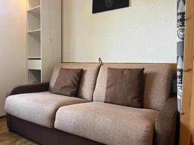 a brown couch with two pillows in a room at Studio chaleureux avec balcon au centre de Samoëns - FR-1-624-83 in Samoëns
