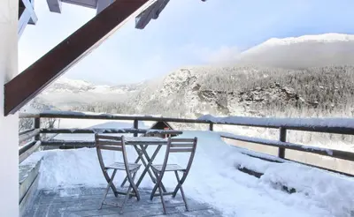 a table and chairs on a balcony with snow covered mountains at Les Grand Balcon - 2ch - 2 balcons - Randonnée - Escalade - Lac des Chavants in Les Houches