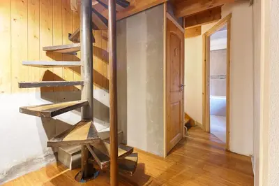 a wooden spiral staircase in a room with a door at Chalet of the 5 Chardons ski-in ski-out in Les Houches