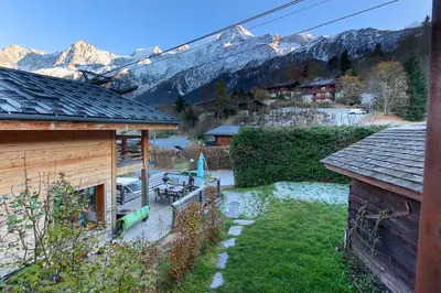 a house with a yard with a table and chairs at Chalet of the 5 Chardons ski-in ski-out in Les Houches