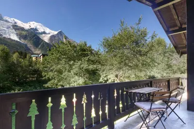 a balcony with a table and chairs and mountains at Les Fleurs de Cham - Jardin vues - Rénové in Chamonix-Mont-Blanc