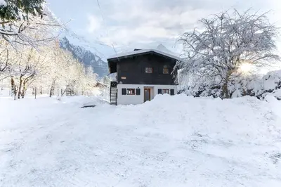 a house is covered in snow in front thereof at Les Fleurs de Cham - Jardin vues - Rénové in Chamonix-Mont-Blanc