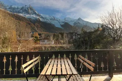 a wooden bench sitting on top of a balcony with mountains at Les Fleurs de Cham - Jardin vues - Rénové in Chamonix-Mont-Blanc