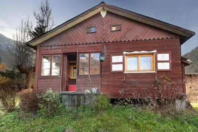 a small wooden house with a red door in a field at Le Petite Chalet Tourmente in Chamonix-Mont-Blanc