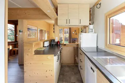 a kitchen with wooden cabinets and a white refrigerator at Le Petite Chalet Tourmente in Chamonix-Mont-Blanc