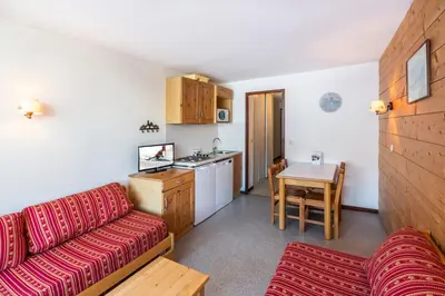 a living room with a red couch and a kitchen at Vacancéole - Résidence Grand Morillon in Morillon