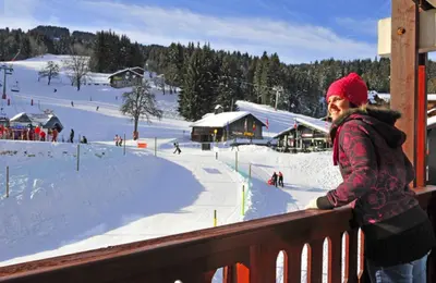 a woman standing on a balcony looking at a ski resort at Vacancéole - Résidence Grand Morillon in Morillon