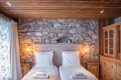 a bedroom with two beds and a stone wall at Paccard Locations Chamonix in Chamonix-Mont-Blanc