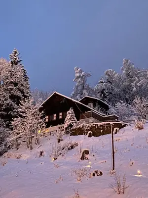 a house covered in snow in front of trees at Chalet Keller in Les Contamines-Montjoie