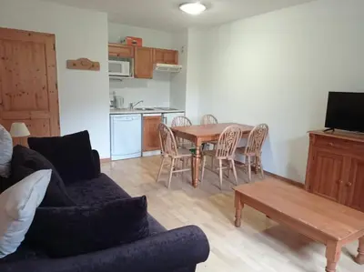 a living room with a couch and a table with chairs at Bel Appartement en résidence avec piscines in Samoëns