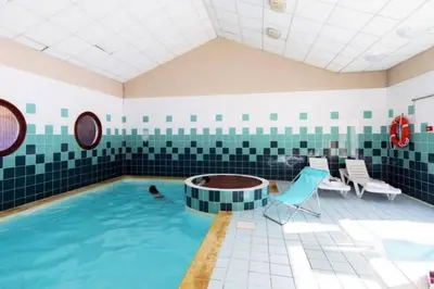 a pool in a room with a person in the water at Bel Appartement en résidence avec piscines in Samoëns