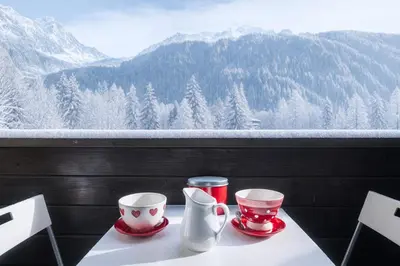 a table with two coffee cups and a view of mountains at Bel Apt Near The Slopes Argentiere in Chamonix-Mont-Blanc