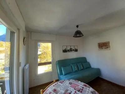 a living room with a blue couch and a window at Samoëns - Studio Les Espaces in Samoëns