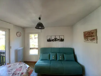 a living room with a green couch and a bed at Samoëns - Studio Les Espaces in Samoëns