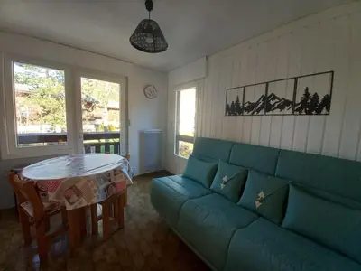 a living room with a green couch and a table at Samoëns - Studio Les Espaces in Samoëns