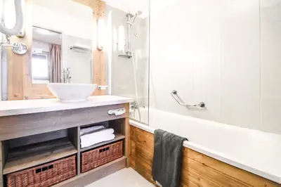 a bathroom with a sink and a tub and a mirror at Newly redecorated 2-bed ski-in ski-out family apartment in Flaine
