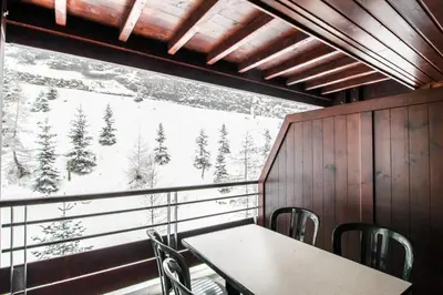 a table and chairs in a room with a large window at Newly redecorated 2-bed ski-in ski-out family apartment in Flaine