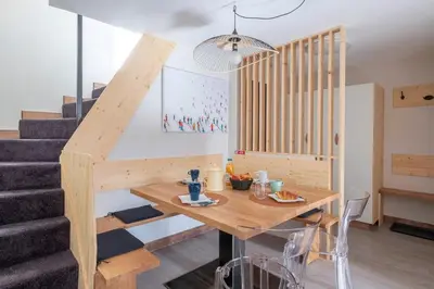 a dining room with a wooden table and stairs at L'Appart 52, magnifique duplex en plein coeur de Chamonix-Mont-Blanc in Chamonix-Mont-Blanc