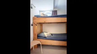 a bedroom with two bunk beds and a chair at L'Appart 52, magnifique duplex en plein coeur de Chamonix-Mont-Blanc in Chamonix-Mont-Blanc