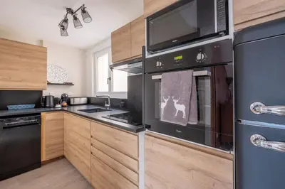 a kitchen with black appliances and wooden cabinets at L'Appart 52, magnifique duplex en plein coeur de Chamonix-Mont-Blanc in Chamonix-Mont-Blanc