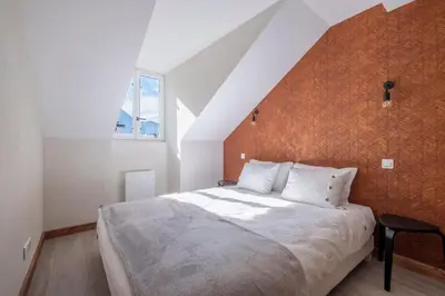 a bedroom with a large bed with an orange wall at L'Appart 52, magnifique duplex en plein coeur de Chamonix-Mont-Blanc in Chamonix-Mont-Blanc