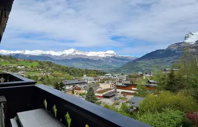 a view from a balcony of a town with snow capped mountains at Alpenrose in Saint-Gervais-les-Bains