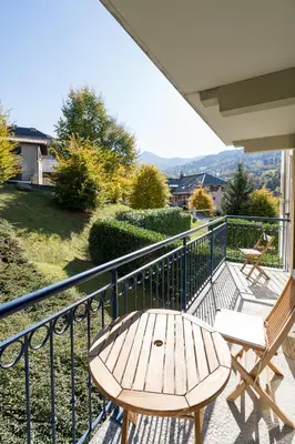 a wooden table and two chairs on a balcony at Comme un chalet, appartement à la montagne in Saint-Gervais-les-Bains