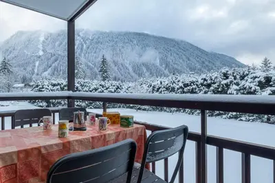 a table and chairs on a balcony with snow covered mountains at Apartment With Balcony Close To The Ski Slopes in Chamonix-Mont-Blanc
