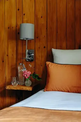 a lamp and a vase with flowers on a bed at Auberge des Gorges - Restaurant Gastronomique & Chambres in Servoz