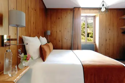 a bed with an orange pillow and a lamp on a wooden wall at Auberge des Gorges - Restaurant Gastronomique & Chambres in Servoz
