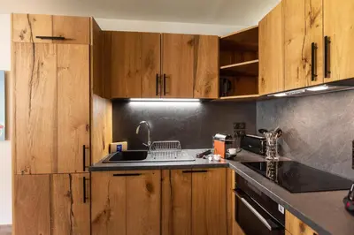 a kitchen with wooden cabinets and a sink at Résidence Club MMV Samoens Village in Samoëns
