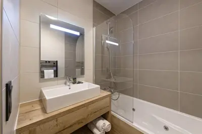 a bathroom with a sink and a shower and a tub at Résidence Club MMV Samoens Village in Samoëns
